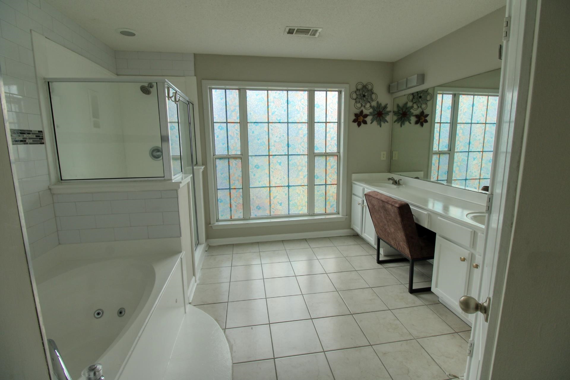 25 Whispering Ridge Cove Oakland, TN 38060 - Photo 12 of 19 Spacious bath featuring a corner soaking tub, glass-enclosed shower, dual vanity with integrated sinks, and ample natural light