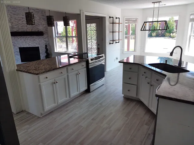 a kitchen with granite countertop a stove a sink and a refrigerator