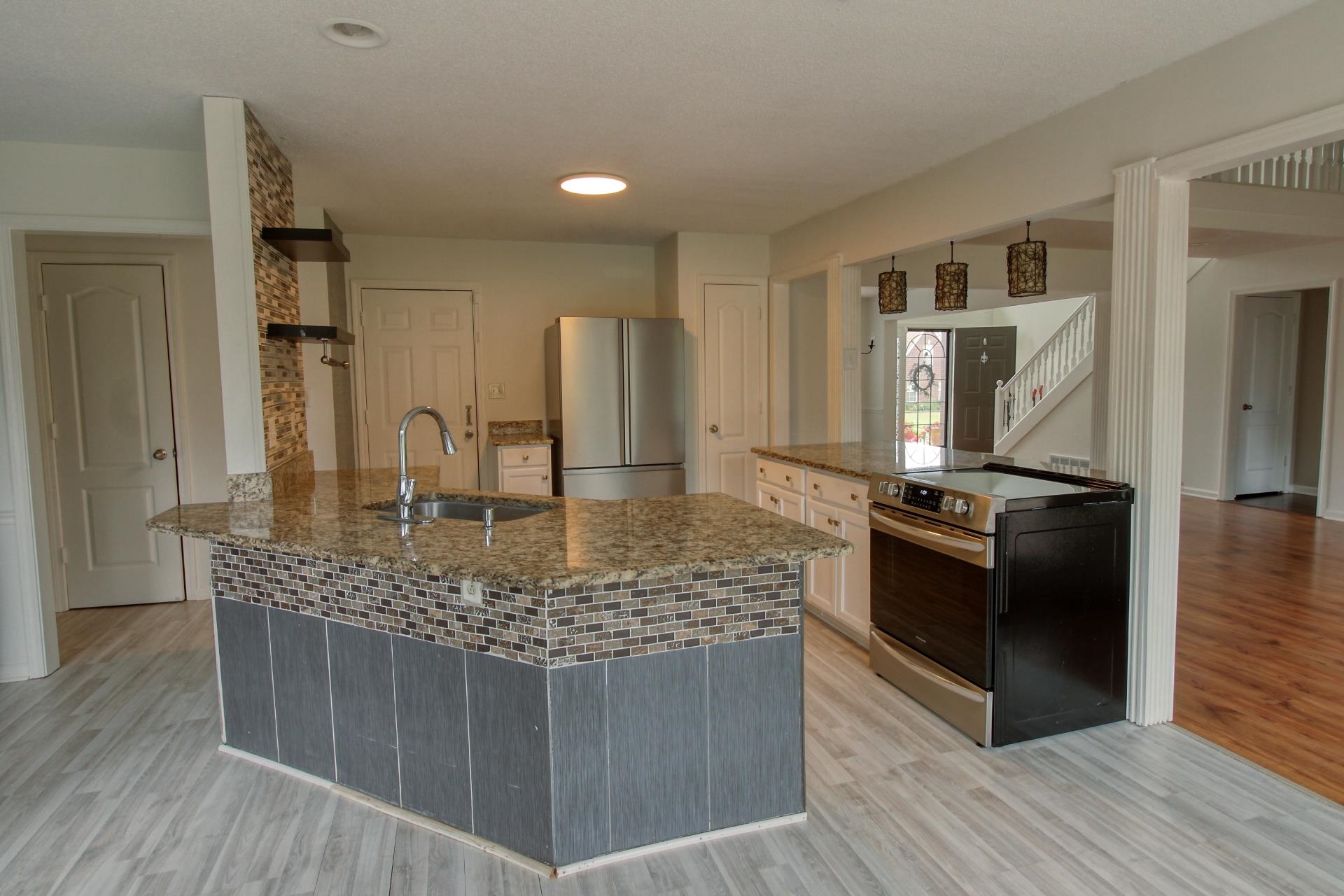 25 Whispering Ridge Cove Oakland, TN 38060 - Photo 4 of 19 Kitchen featuring a granite-topped island with an undermount sink and mosaic tile detailing