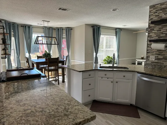 a kitchen with granite countertop a stove a sink and a dining table