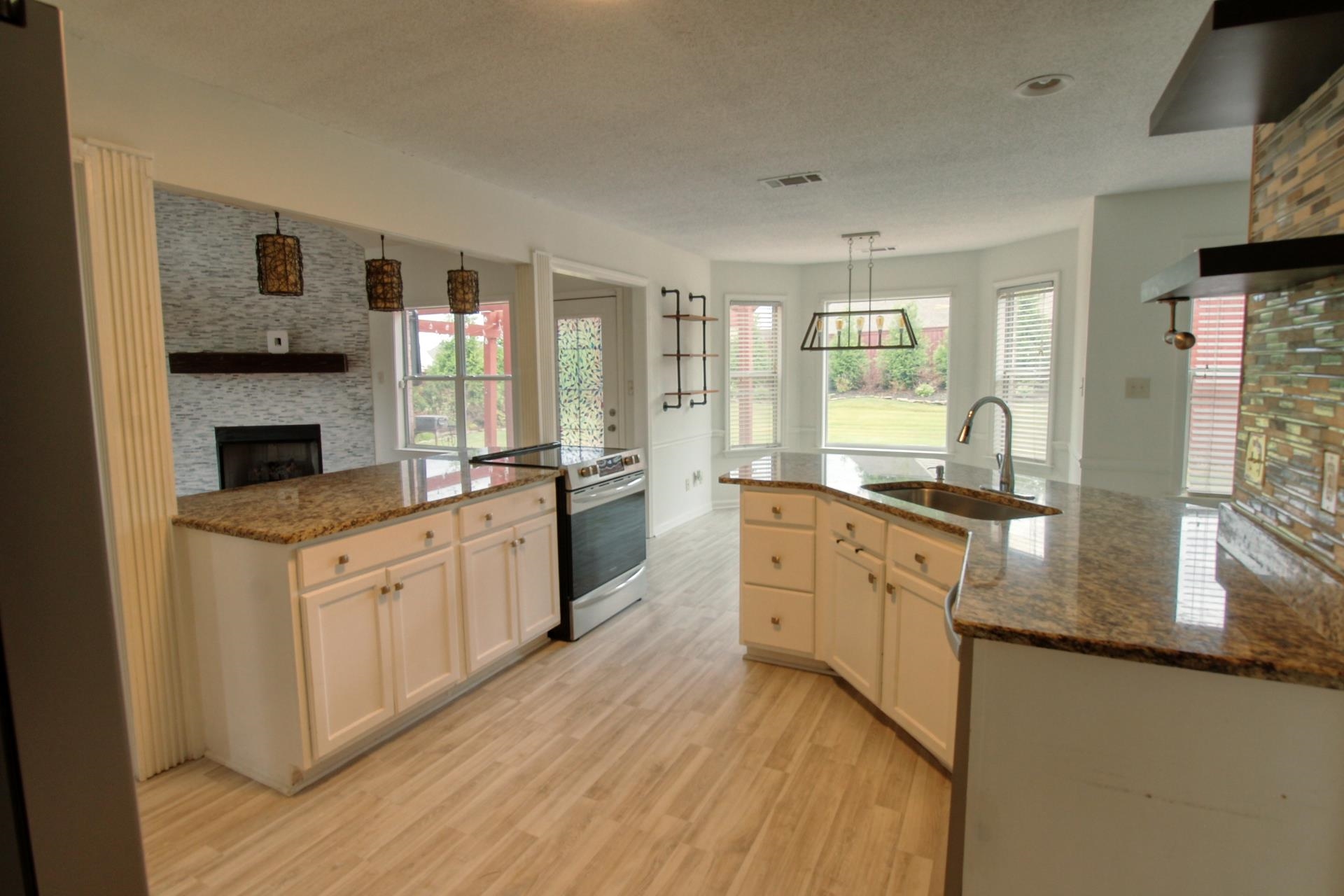 25 Whispering Ridge Cove Oakland, TN 38060 - Photo 5 of 19 Kitchen featuring wood-finish flooring, granite countertops, white cabinetry, a stainless steel oven, and a bay window