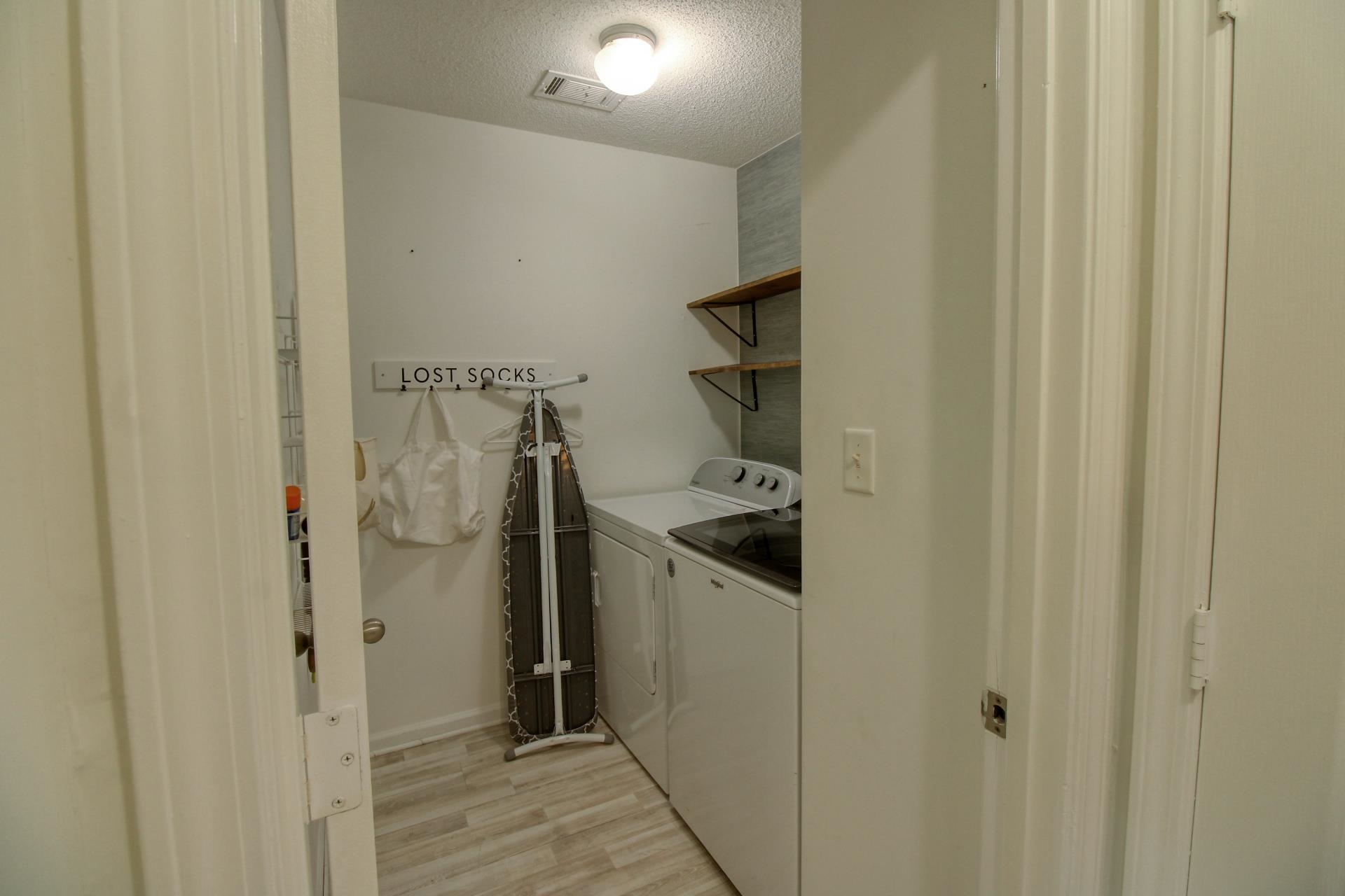 25 Whispering Ridge Cove Oakland, TN 38060 - Photo 9 of 19 Dedicated laundry area featuring wood-finish flooring, light grey wall tile, and two mounted wood shelves