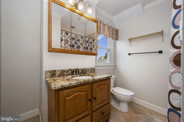 a bathroom with a granite countertop toilet sink and mirror