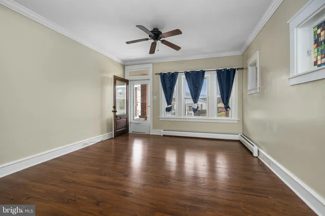 an empty room with wooden floor ceiling fan and window
