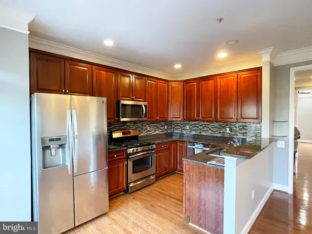 a kitchen with stainless steel appliances granite countertop refrigerator a stove top oven a sink and dishwasher with wooden floor
