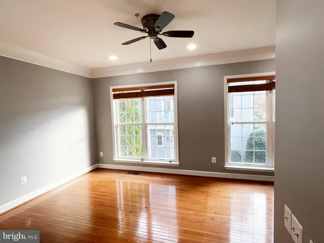a view of an empty room with window and wooden floor
