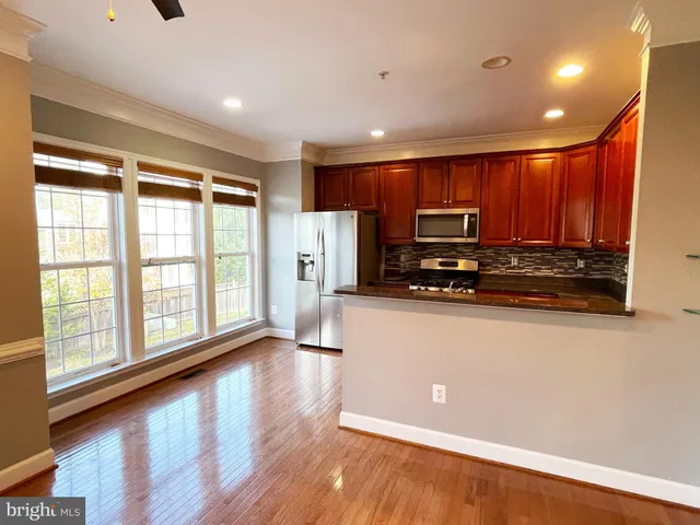 a view of kitchen with stainless steel appliances wooden floor and large window