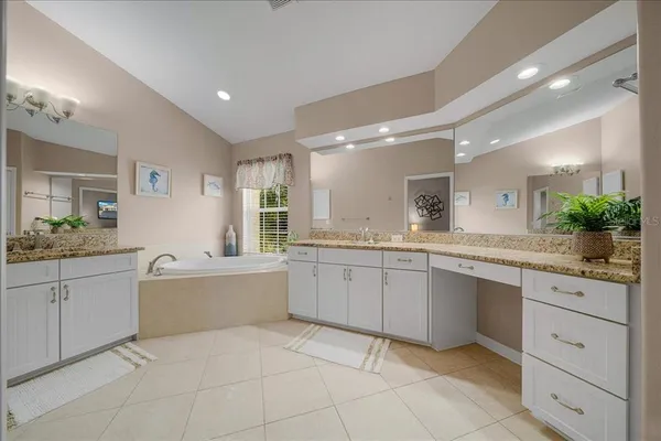 a large white bathroom with a granite countertop sink and a mirror