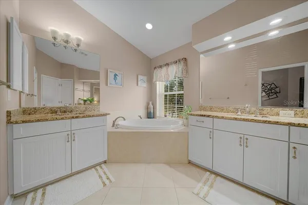 a bathroom with a granite countertop sink mirror and a bathtub
