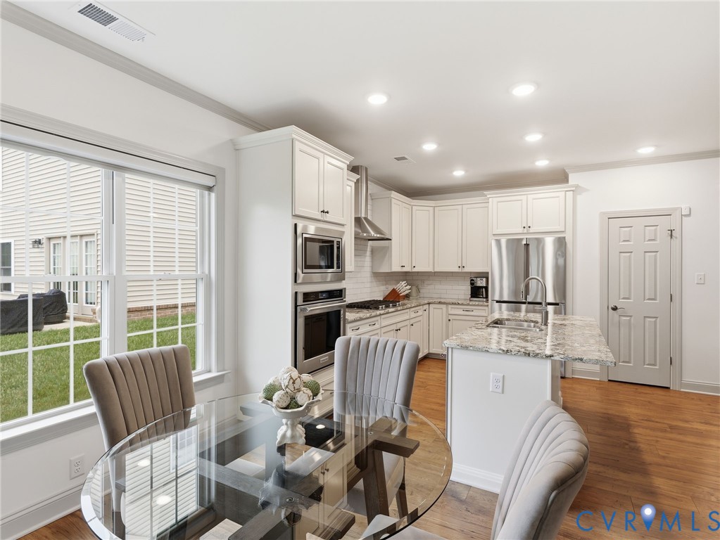12520 Donahue Road Glen Allen, VA 23059 - Photo 8 of 35 a large kitchen with stainless steel appliances kitchen island granite countertop a refrigerator a stove a sink dishwasher with a dining table and chairs with wooden floor