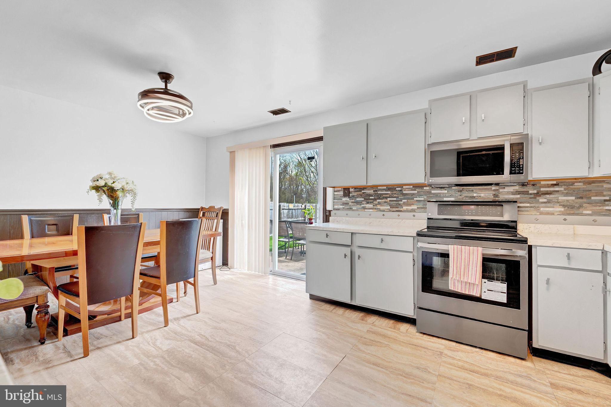 6 Transom Court Elkton, MD 21921 - Photo 12 of 33 a kitchen with stainless steel appliances granite countertop a stove top oven a sink dishwasher a dining table and chairs with wooden floor