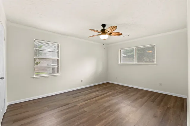 a view of an empty room with a window and wooden floor