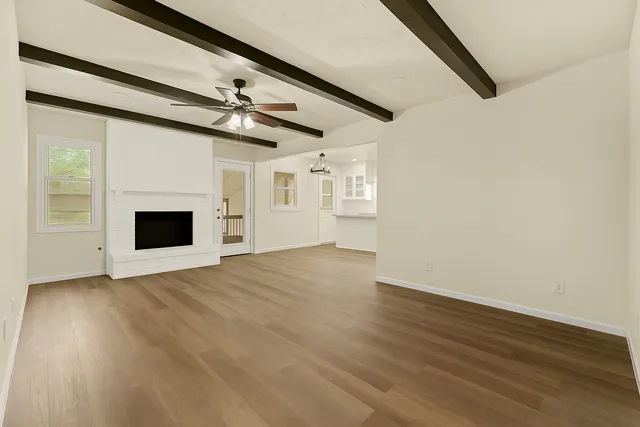 a view of a livingroom with wooden floor a ceiling fan and window