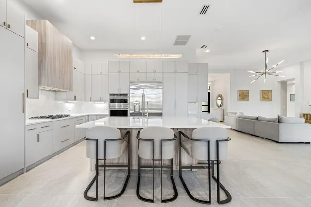 a kitchen with stainless steel appliances kitchen island granite countertop a dining table chairs and white cabinets