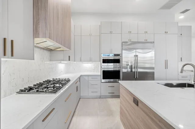 a kitchen with stainless steel appliances kitchen island granite countertop a sink stove and refrigerator