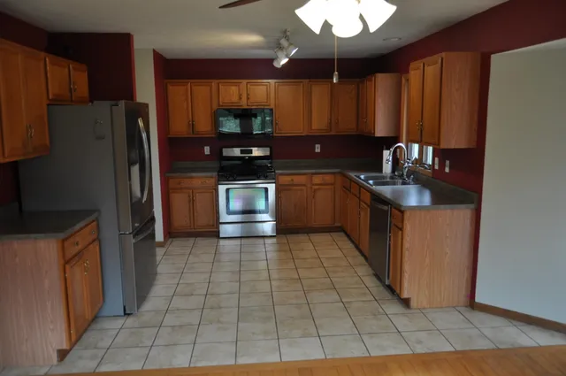 a kitchen with stainless steel appliances granite countertop a refrigerator a sink a stove a microwave and island