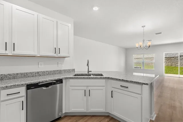 a kitchen with granite countertop stainless steel appliances white cabinets granite counter tops and a wooden floors