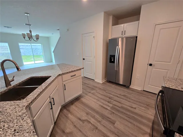 a kitchen with stainless steel appliances a refrigerator sink and wooden floor