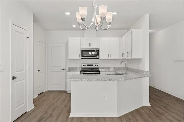 a kitchen with kitchen island granite countertop stainless steel appliances a sink cabinets and wooden floor