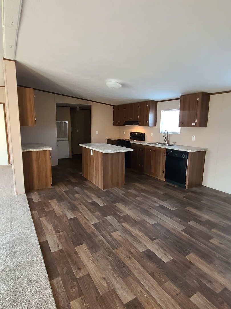 303 Seba Street Hurst, IL 62949 - Photo 8 of 13 a view of a kitchen with a stove top oven a sink dishwasher a dining table and chairs with wooden floor