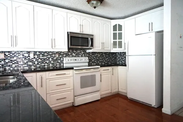 a kitchen with white cabinets and appliances