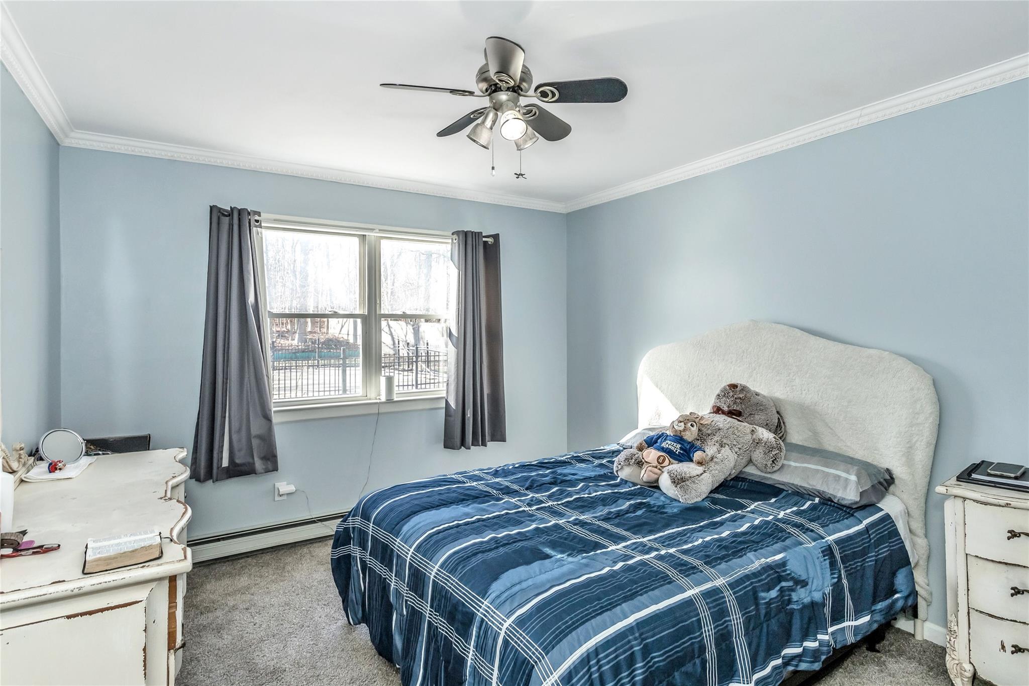9 Bayberry Road Wading River, NY 11792 - Photo 11 of 17 Bedroom with ceiling fan, ornamental molding, light carpet, and a baseboard heating unit