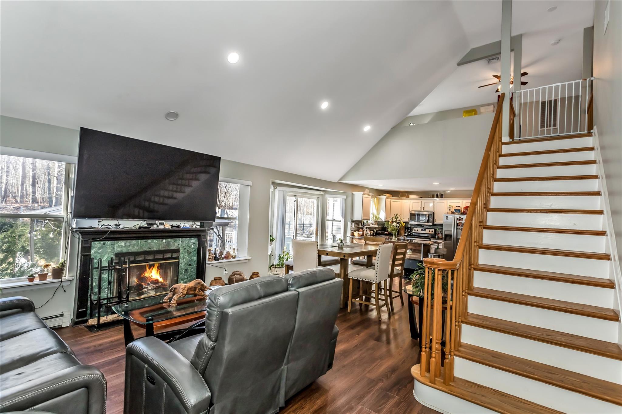 9 Bayberry Road Wading River, NY 11792 - Photo 5 of 17 Living room with a baseboard heating unit, high vaulted ceiling, dark hardwood / wood-style flooring, a fireplace, and ceiling fan
