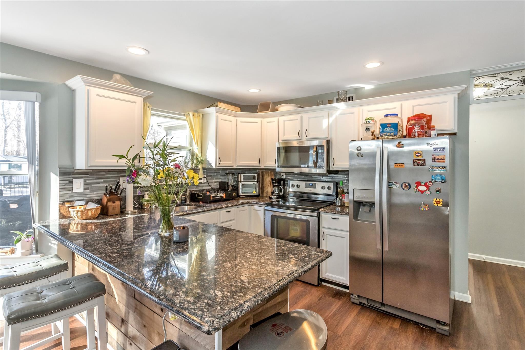 9 Bayberry Road Wading River, NY 11792 - Photo 7 of 17 Kitchen featuring stainless steel appliances, dark stone countertops, tasteful backsplash, and white cabinetry