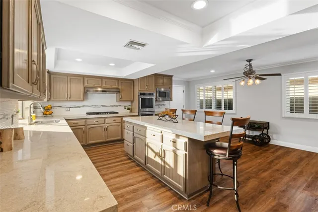 a large kitchen with a large counter top space a sink stainless steel appliances and cabinets
