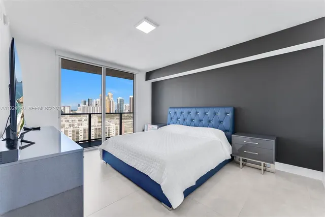 a large bed sitting in a bedroom next to a larger window and a kitchen