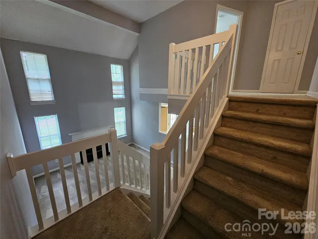 a view of staircase with lots of frames on wall and a window