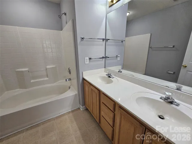 a bathroom with a double vanity sink a mirror and a bathtub