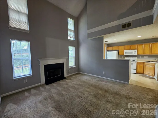 an empty room with windows and fireplace