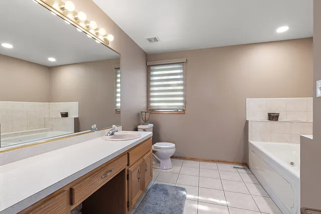 a bathroom with a sink a toilet a tub and a mirror