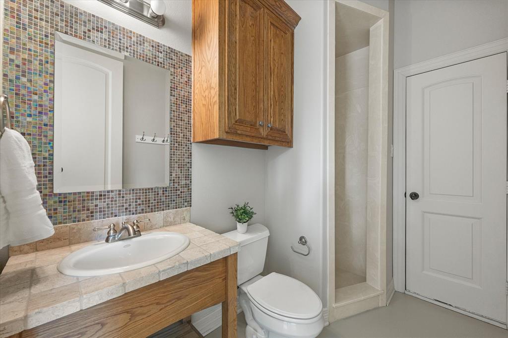161 Ridgemont Road Heath, TX 75126 - Photo 19 of 40 a bathroom with a granite countertop sink a toilet a mirror and shower
