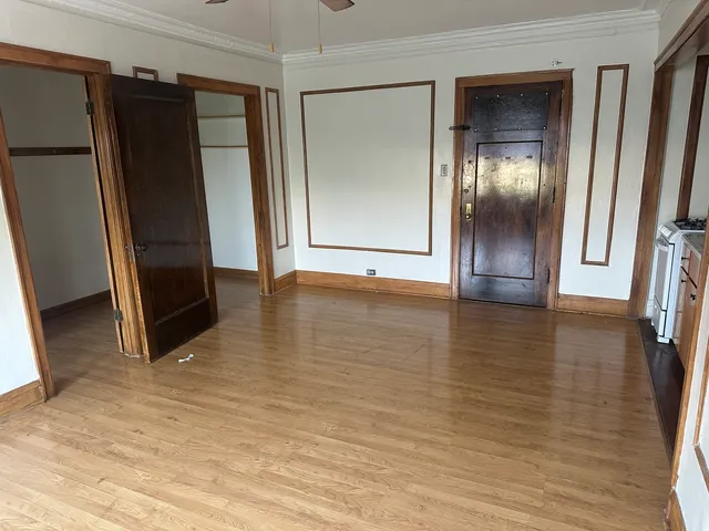 an empty room with wooden floor and a ceiling fan