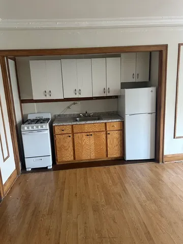 a kitchen with stainless steel appliances granite countertop a refrigerator a stove and a sink with wooden floors