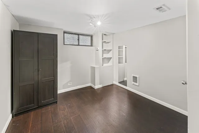 an empty room with a wooden cabinet and windows
