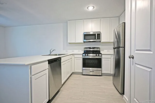 a kitchen with stainless steel appliances a refrigerator a sink a stove and a window