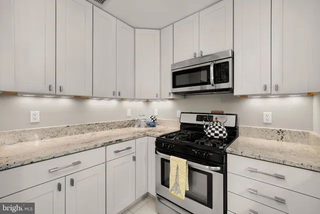 a kitchen with granite countertop white cabinets and stainless steel appliances
