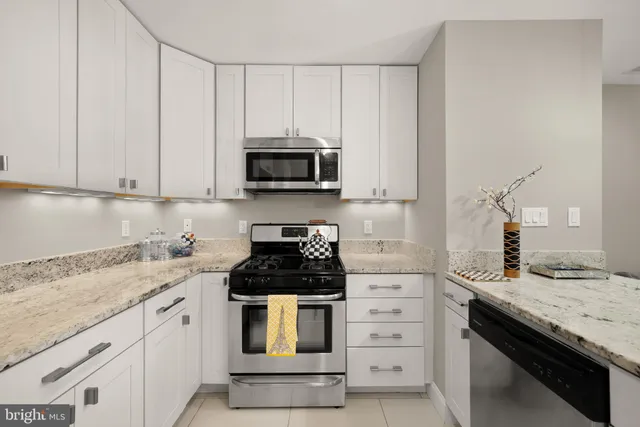 a kitchen with granite countertop white cabinets and stainless steel appliances