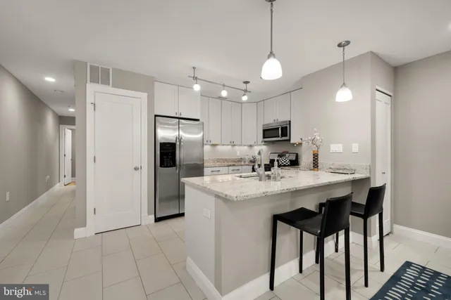 a kitchen with stainless steel appliances granite countertop a refrigerator a sink dishwasher a stove and a refrigerator with wooden floor