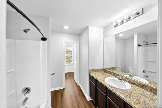 a bathroom with a granite countertop double vanity sink and mirror