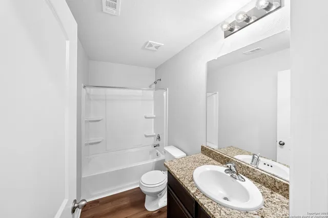 a bathroom with a granite countertop sink toilet a mirror and shower