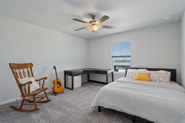 a bedroom with a bed a chair and a potted plant on a dresser