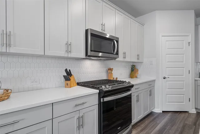 a kitchen with stainless steel appliances white cabinets and a stove top oven