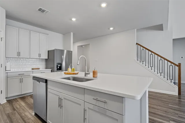 a kitchen with a sink a refrigerator and white cabinets