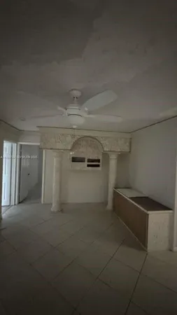 a view of a refrigerator in kitchen and an empty room