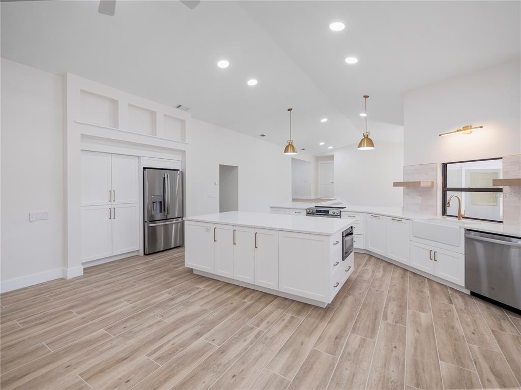 6790 Edgeworth Drive Orlando, FL 32819 - Photo 12 of 57 a large white kitchen with stainless steel appliances refrigerator stove and wooden floor