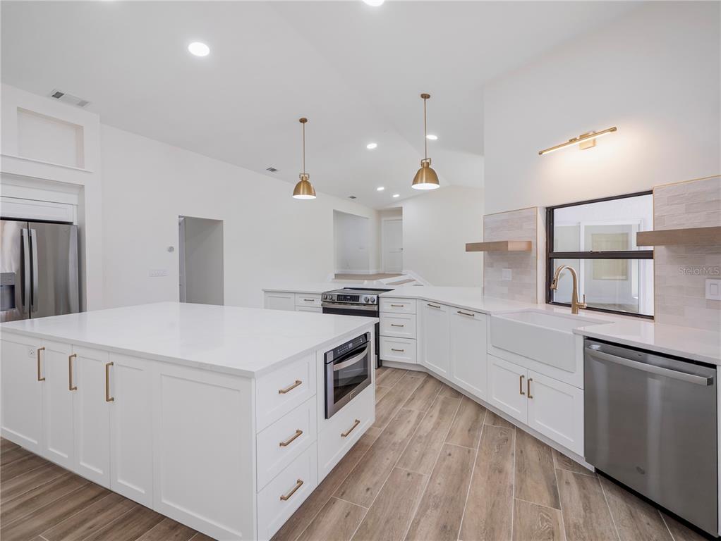 6790 Edgeworth Drive Orlando, FL 32819 - Photo 14 of 57 a large white kitchen with stainless steel appliances
